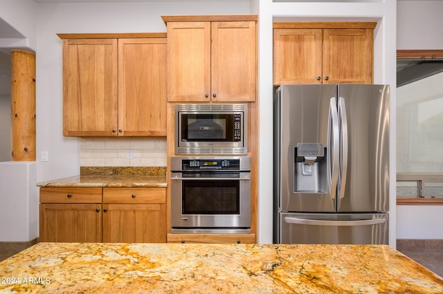 kitchen featuring decorative backsplash, stainless steel appliances, and light stone counters