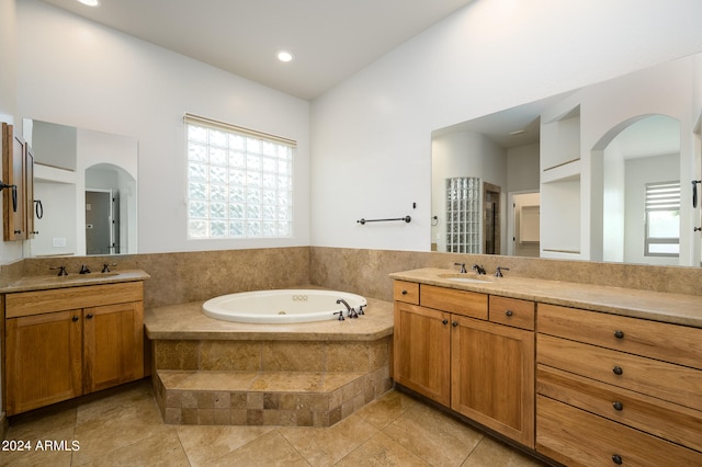 bathroom with tiled tub, vanity, and tile patterned floors