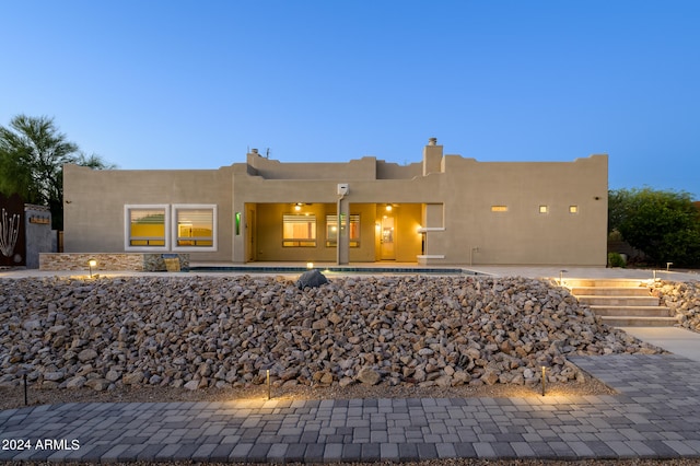 back house at dusk with a pool and a patio area