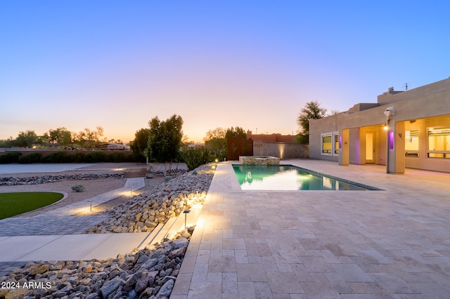 pool at dusk featuring a patio area