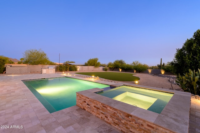 pool at dusk with an in ground hot tub