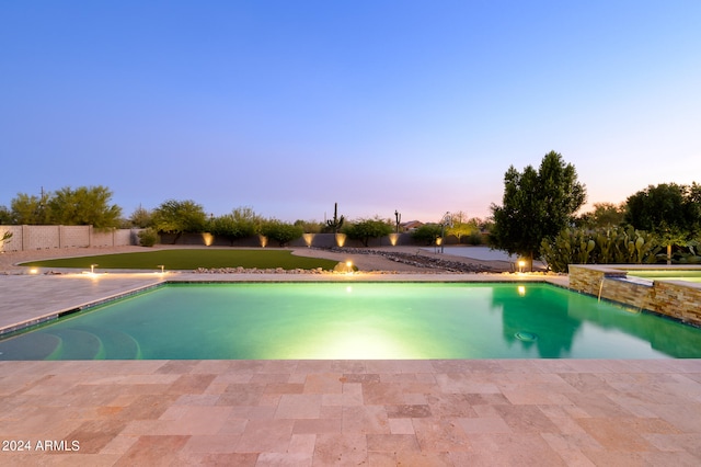 pool at dusk featuring a yard and a patio