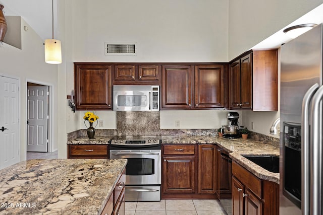 4131 E Cascalote Dr, Cave Creek, AZ 85331 - kitchen with stainless steel appliances, light stone countertops, a towering ceiling, light tile patterned flooring, and hanging light fixtures