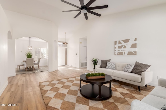 living room with ceiling fan, light hardwood / wood-style flooring, and high vaulted ceiling