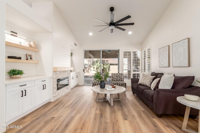 living room featuring a stone fireplace, light hardwood / wood-style flooring, and vaulted ceiling