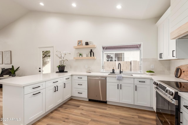 kitchen with white cabinets, kitchen peninsula, sink, and appliances with stainless steel finishes