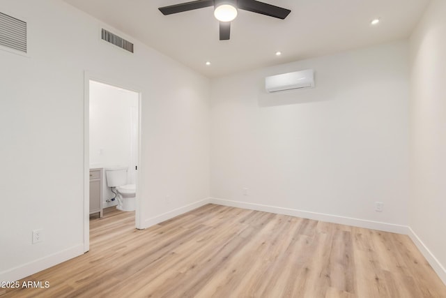 interior space featuring ensuite bathroom, ceiling fan, light hardwood / wood-style flooring, and a wall mounted AC