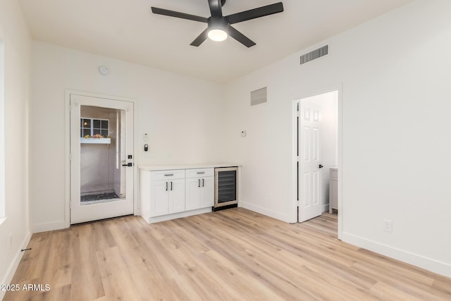 unfurnished room featuring ceiling fan, beverage cooler, and light hardwood / wood-style flooring