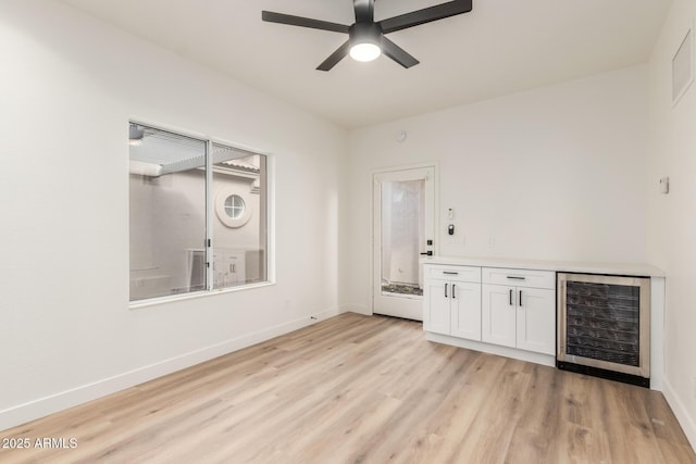 interior space featuring white cabinets, ceiling fan, wine cooler, and light hardwood / wood-style flooring