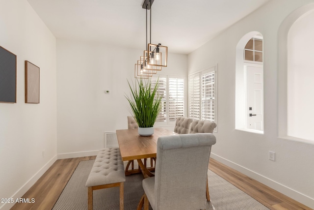 dining space featuring wood-type flooring and an inviting chandelier