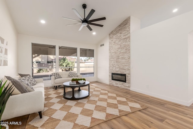 living room with ceiling fan, a fireplace, high vaulted ceiling, and light hardwood / wood-style floors