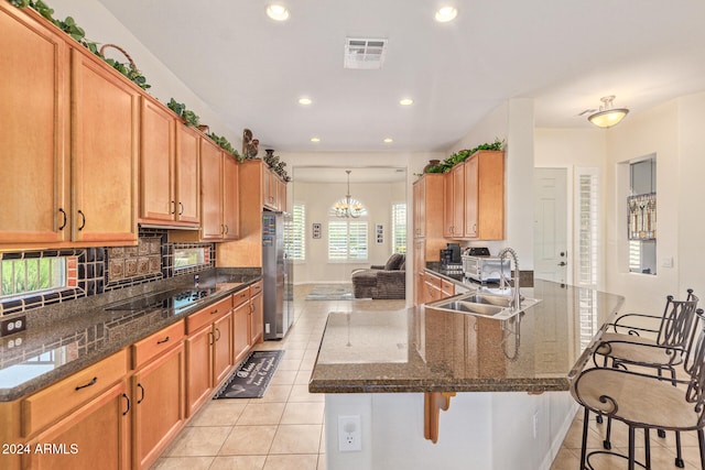 kitchen with dark stone countertops, light tile patterned floors, sink, and a breakfast bar