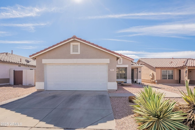 view of front facade with a garage, concrete driveway, a tiled roof, fence, and stucco siding