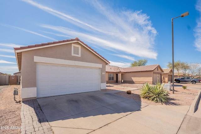 view of front of house featuring driveway, a tiled roof, an attached garage, and stucco siding