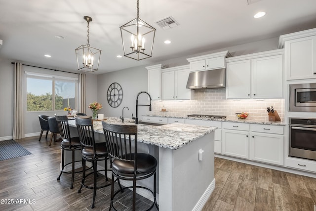 kitchen featuring a center island with sink, white cabinets, and stainless steel appliances