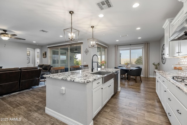 kitchen featuring white cabinets, pendant lighting, sink, and an island with sink