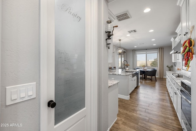 kitchen featuring pendant lighting, sink, an island with sink, appliances with stainless steel finishes, and white cabinetry