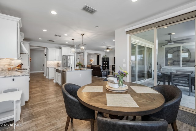 dining room with ceiling fan, sink, and light hardwood / wood-style flooring