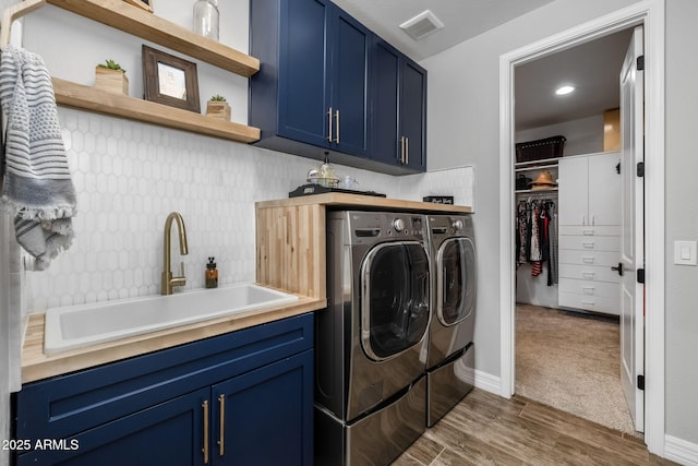 laundry area featuring separate washer and dryer, sink, cabinets, and dark carpet