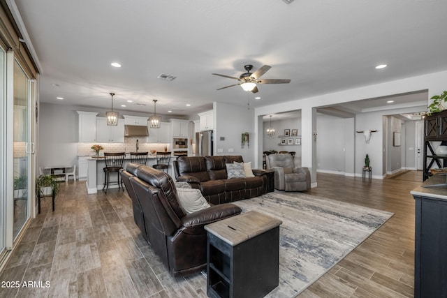 living room with ceiling fan with notable chandelier