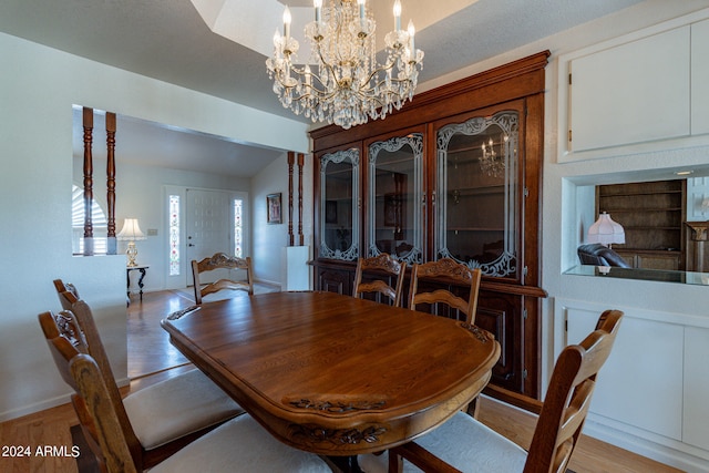 dining room featuring an inviting chandelier, light hardwood / wood-style flooring, and lofted ceiling