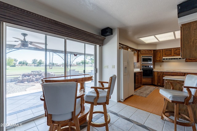 dining room with a textured ceiling, light tile patterned floors, and ceiling fan