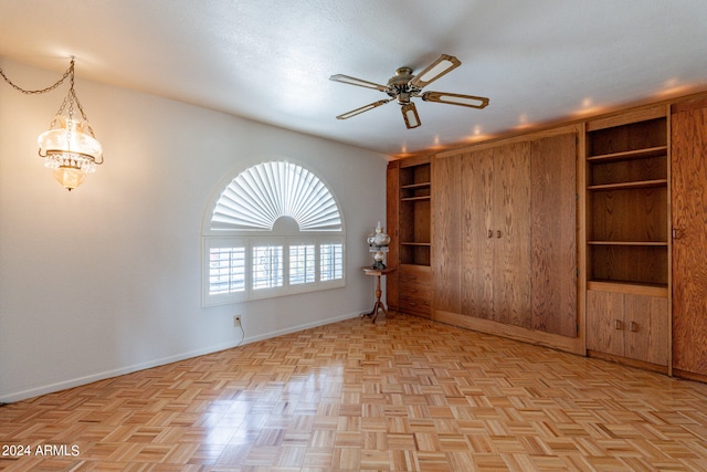 unfurnished room with ceiling fan with notable chandelier and light parquet floors