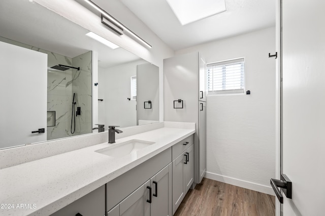 bathroom featuring a tile shower, vanity, and wood-type flooring