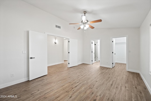 interior space featuring a spacious closet, ceiling fan, light hardwood / wood-style floors, vaulted ceiling, and a closet