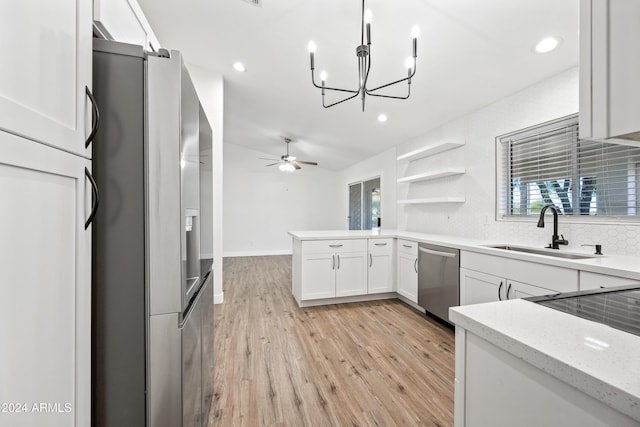 kitchen featuring ceiling fan with notable chandelier, stainless steel appliances, sink, light hardwood / wood-style flooring, and white cabinetry