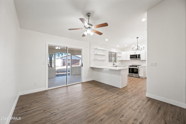 kitchen featuring wood-type flooring, kitchen peninsula, sink, appliances with stainless steel finishes, and white cabinetry