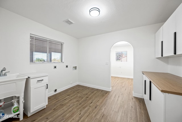 laundry area with cabinets, hookup for a washing machine, a textured ceiling, hookup for an electric dryer, and wood-type flooring