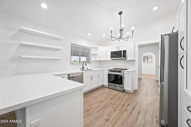 kitchen with white cabinets, sink, light wood-type flooring, appliances with stainless steel finishes, and decorative light fixtures