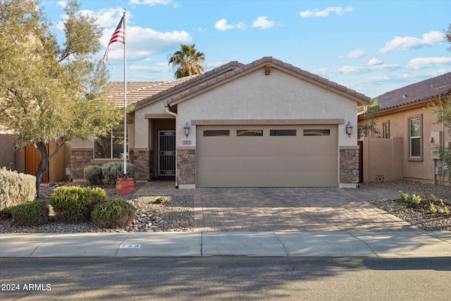 view of front of home featuring stucco siding, driveway, stone siding, fence, and an attached garage