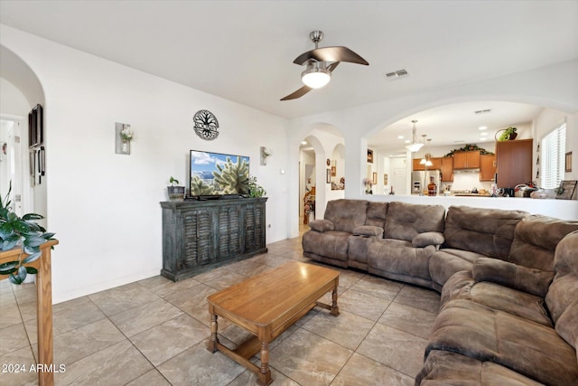 living area with arched walkways, visible vents, and ceiling fan with notable chandelier