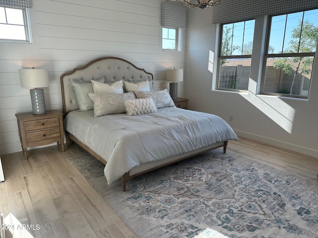 bedroom with multiple windows, hardwood / wood-style flooring, and wooden walls