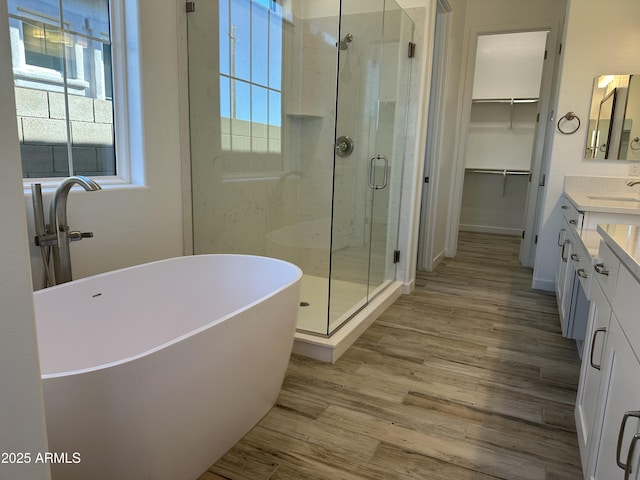 bathroom with plenty of natural light, plus walk in shower, hardwood / wood-style floors, and vanity