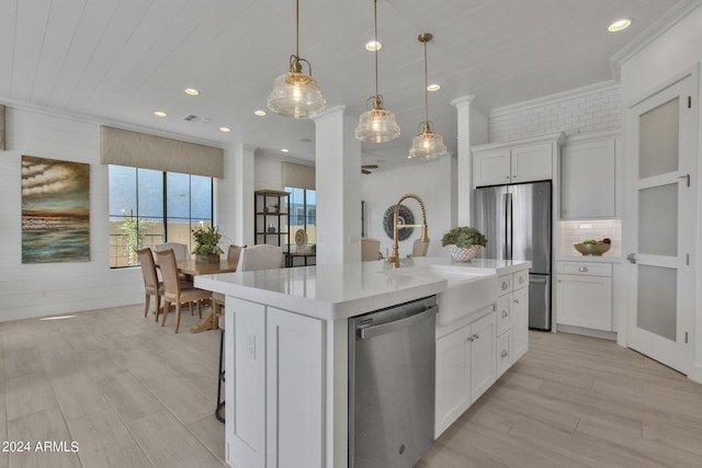 kitchen featuring white cabinetry, sink, hanging light fixtures, a kitchen island with sink, and stainless steel appliances