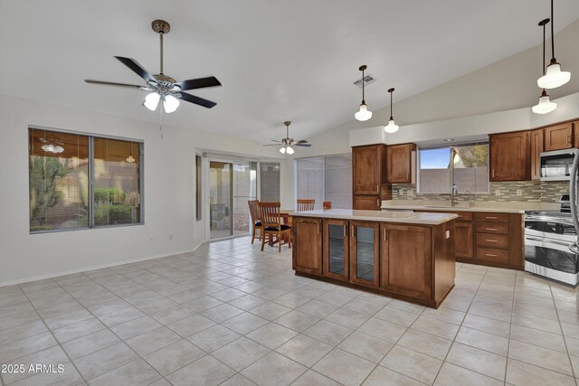 kitchen featuring a kitchen island, sink, light stone countertops, appliances with stainless steel finishes, and lofted ceiling