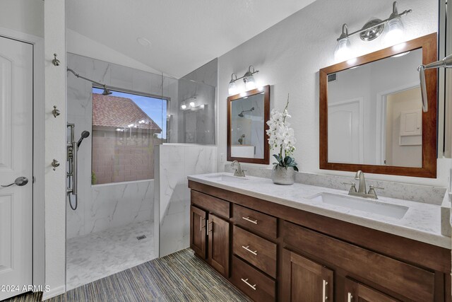 bathroom featuring tiled shower, vaulted ceiling, and vanity