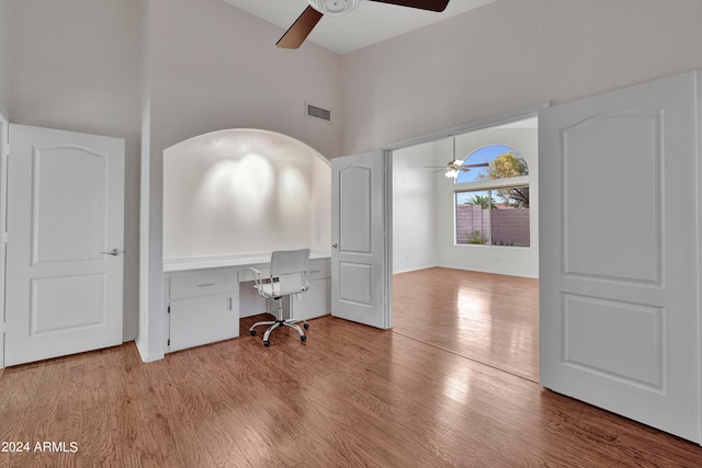 unfurnished office featuring light wood-type flooring, a high ceiling, and ceiling fan