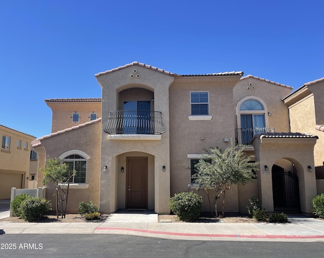 mediterranean / spanish house with a tiled roof, a balcony, and stucco siding