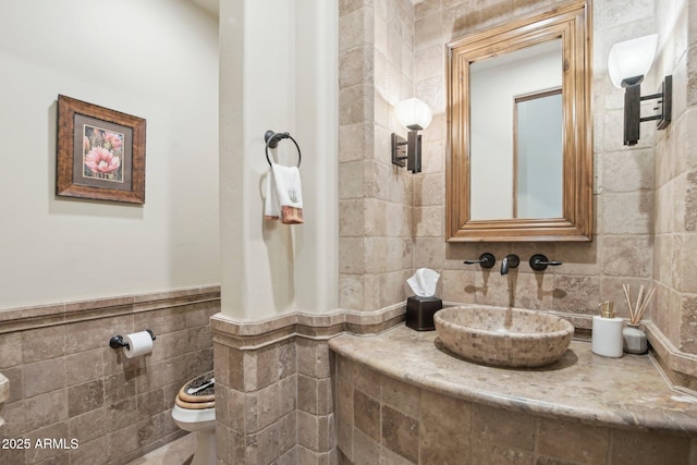 bathroom with a wainscoted wall, tile walls, toilet, and vanity