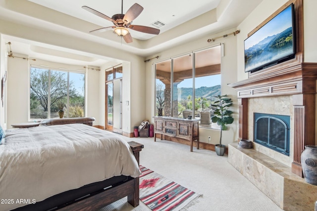 bedroom with visible vents, a raised ceiling, access to exterior, carpet, and a high end fireplace