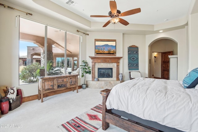 bedroom featuring a tile fireplace, carpet floors, visible vents, baseboards, and a tray ceiling