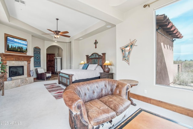 bedroom featuring visible vents, arched walkways, a raised ceiling, carpet flooring, and a high end fireplace