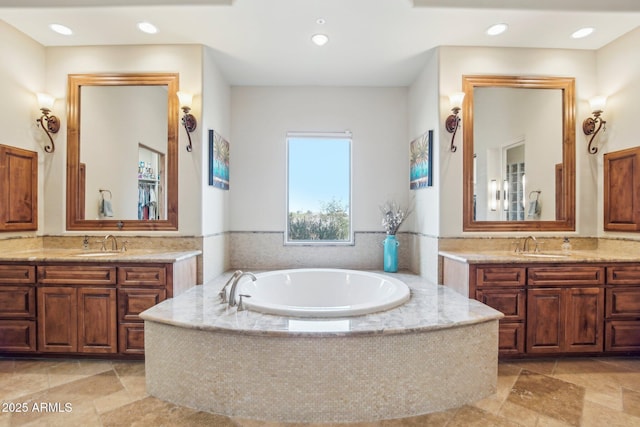 bathroom featuring a sink, a garden tub, two vanities, and recessed lighting