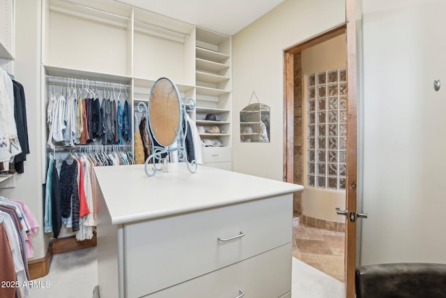 walk in closet featuring stone finish floor