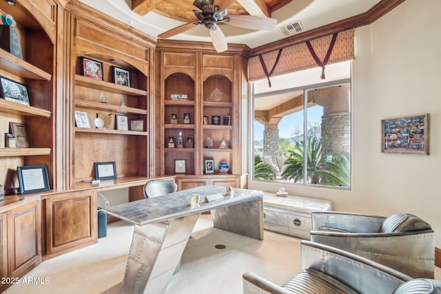 carpeted office space featuring a ceiling fan, visible vents, built in desk, and built in shelves