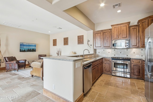 kitchen featuring stainless steel appliances, a sink, light stone countertops, and stone tile floors